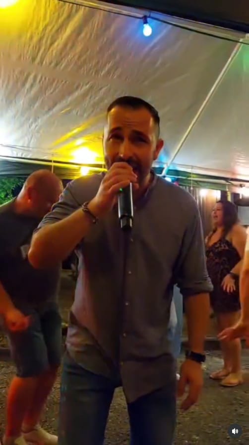 Salva Ditta singt mit Mikrofon bei einer Feier im Zelt, Gäste tanzen im Hintergrund